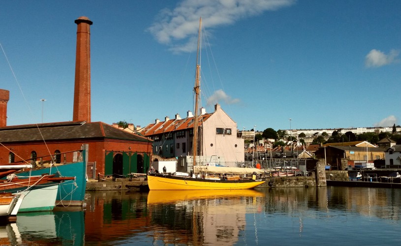 View of Underfall Yard on Bristol Harbourside with a yellow boat on the water in front
